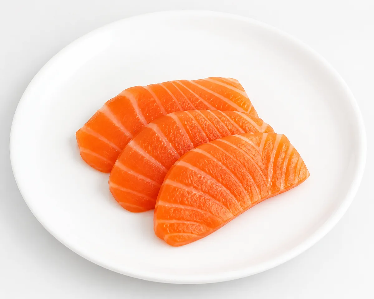 Orange-pink salmon slices with white fat lines on a white plate